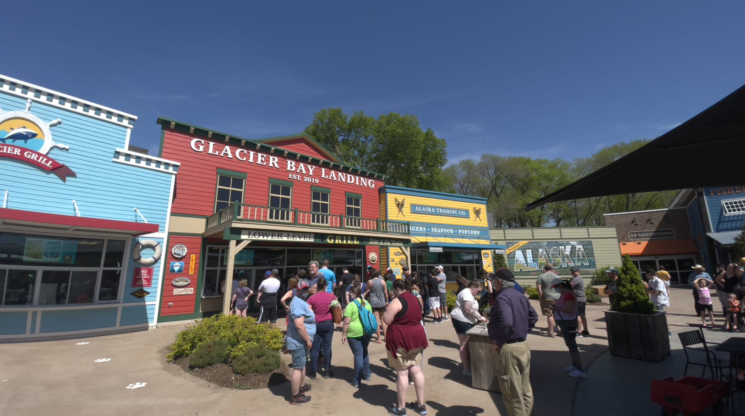 Brightly colored buildings hugged together selling various concessions. "Glacier Bay Landing" is on the sign of the center building. 