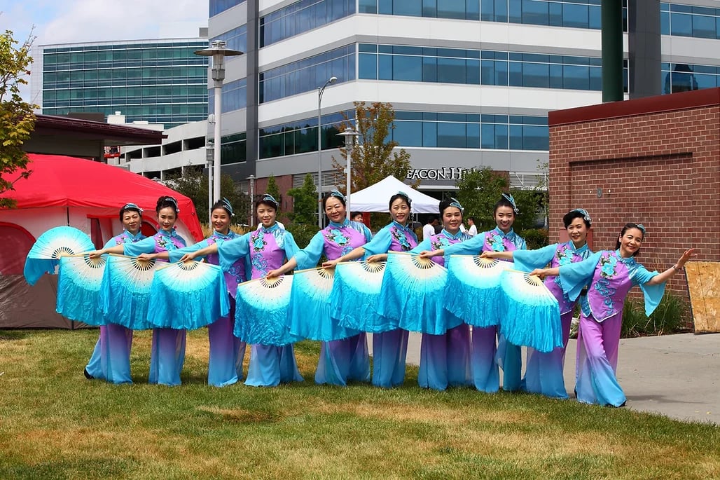 Asian dancers with fans and matching outfits posing for the camera at the One Community Cultural Festival. 